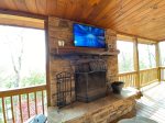 Main floor porch with a wood burning fireplace with a flat screen tv and a gas girll 